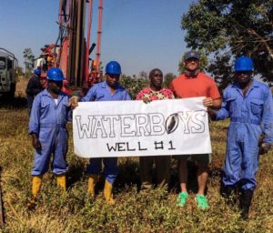 Chris Long with workers holding up the sign for water well number one in Tanzania.